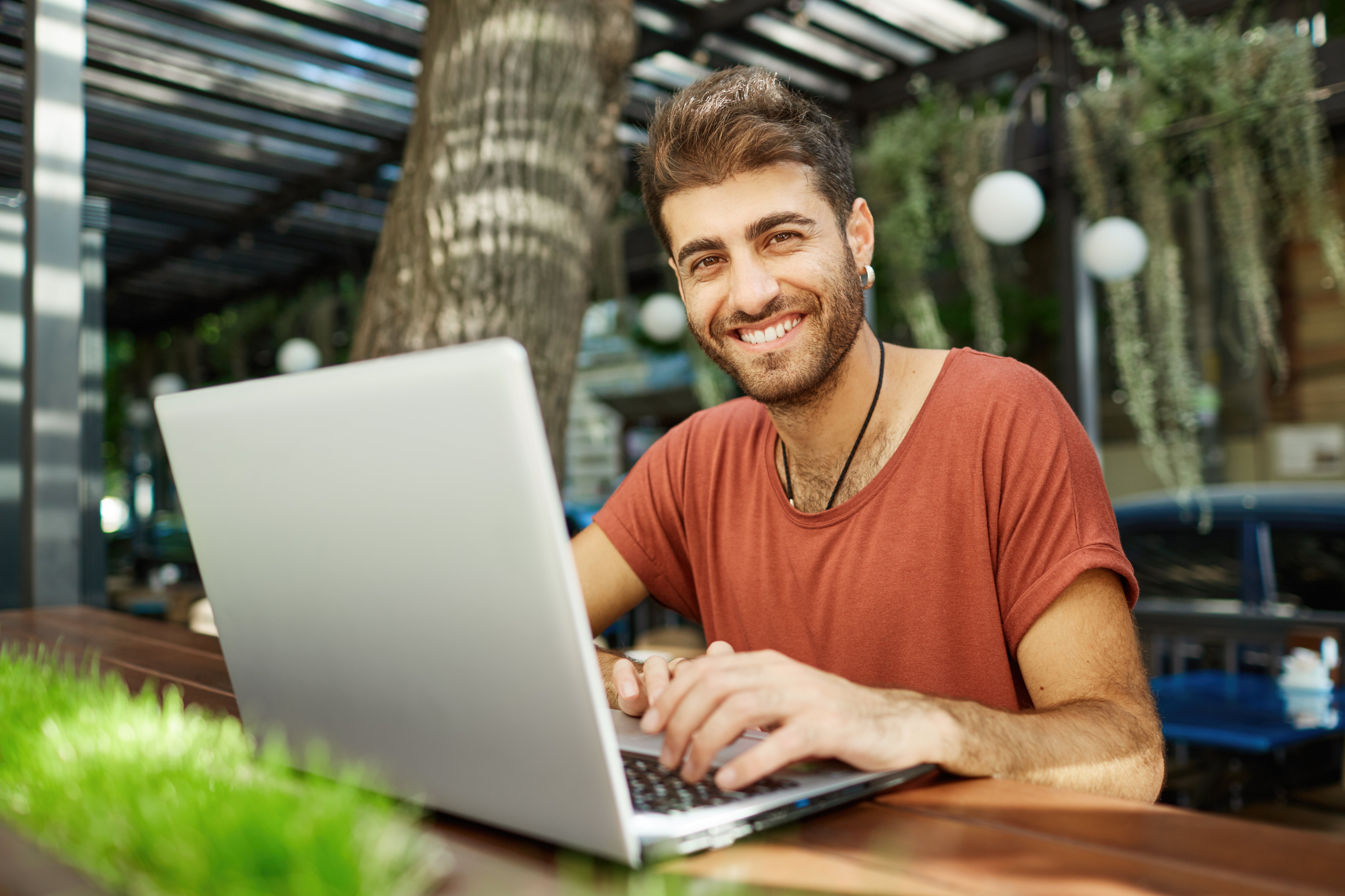 cheerful-handsome-man-talking-with-friend-online-typing-laptop-smiling-happy