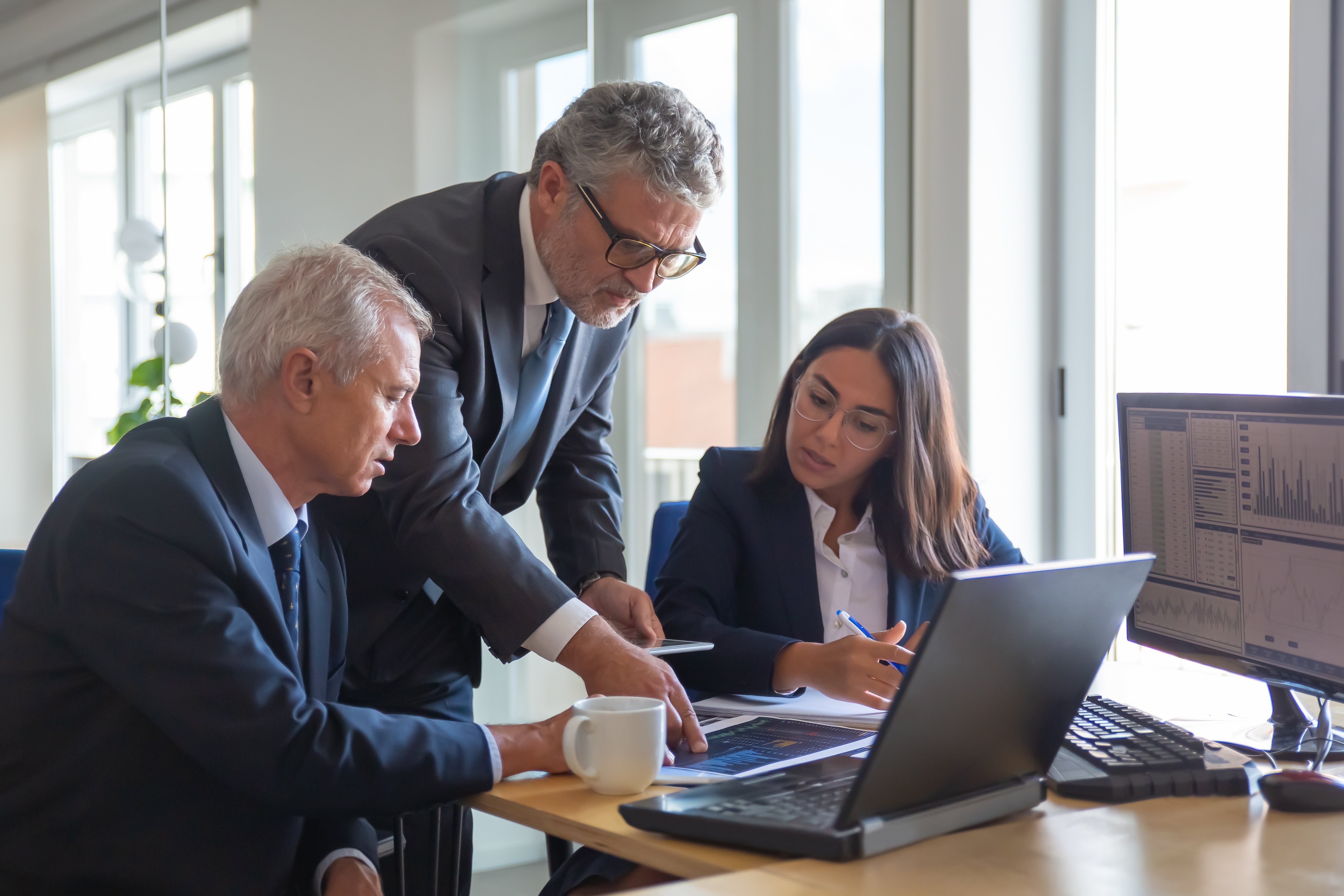 concentrated-colleagues-watching-statistic-charts-and-talking-about-work-professional-senior-managers-and-young-assistant-preparing-business-plan-teamwork-management-and-partnership-concept