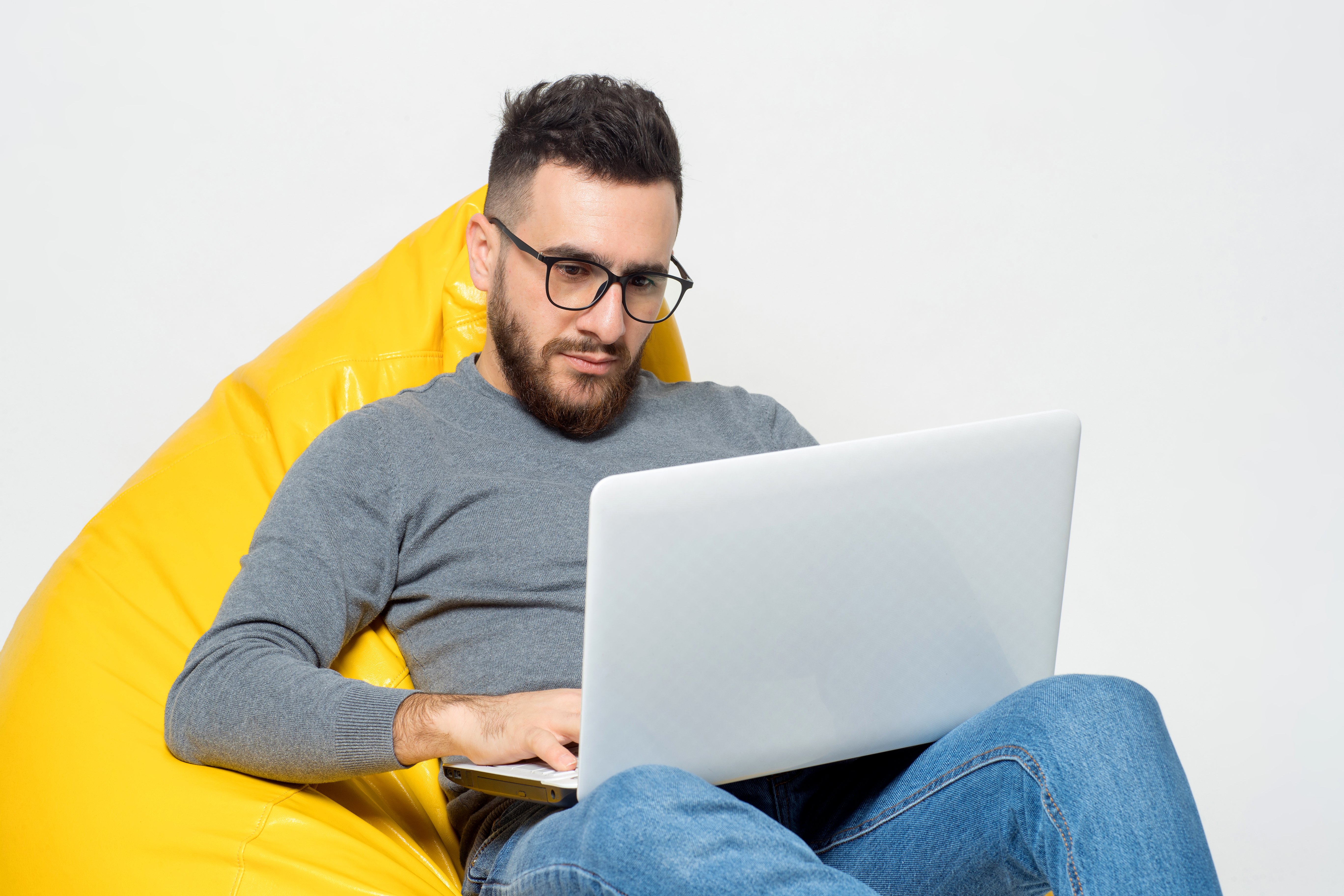 guy-works-with-laptop-while-sitting-yellow-pouf-chair
