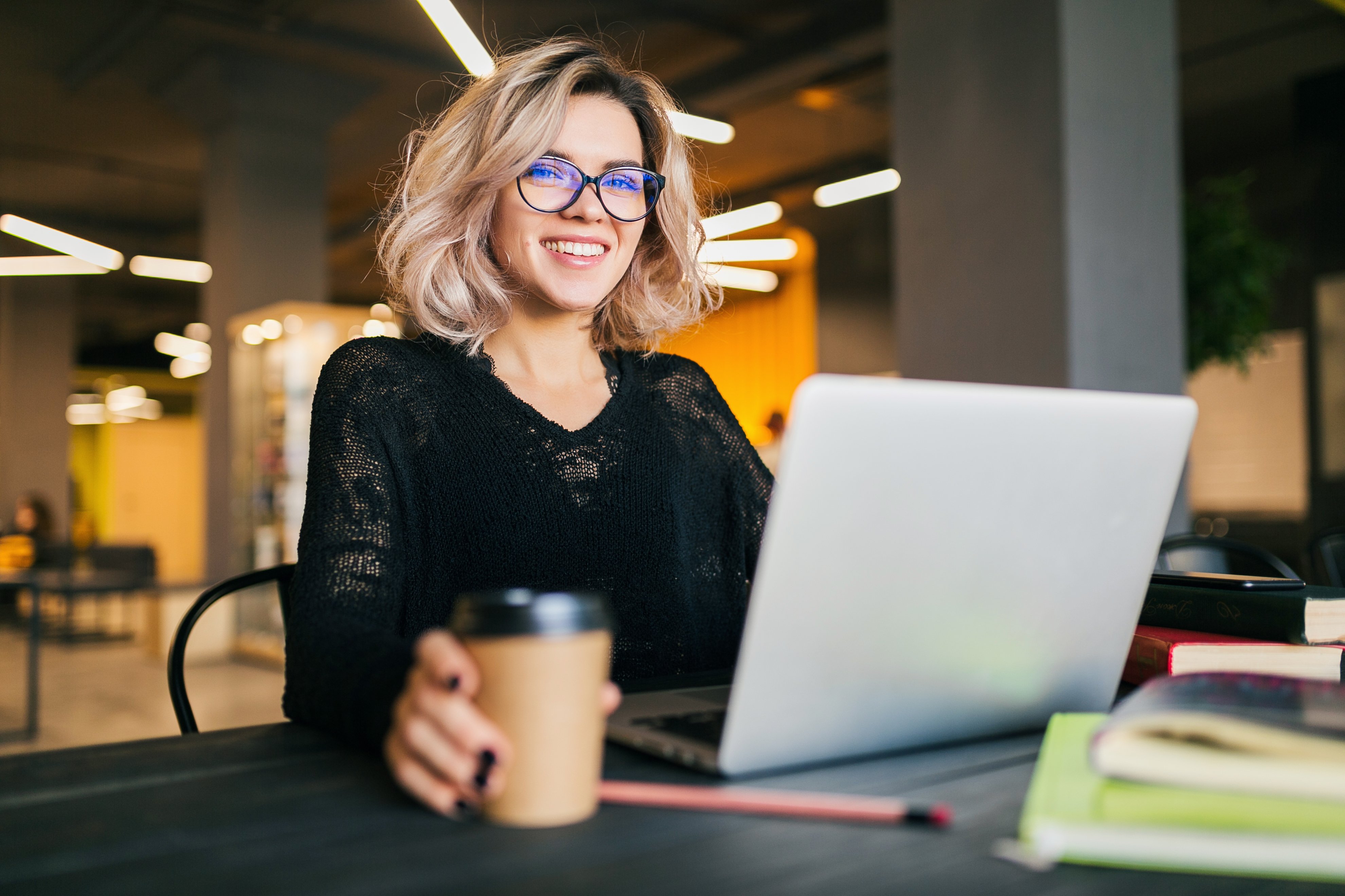 portrait-of-young-pretty-woman-sitting-at-table-in-black-shirt-working-on-laptop-in-co-working-office