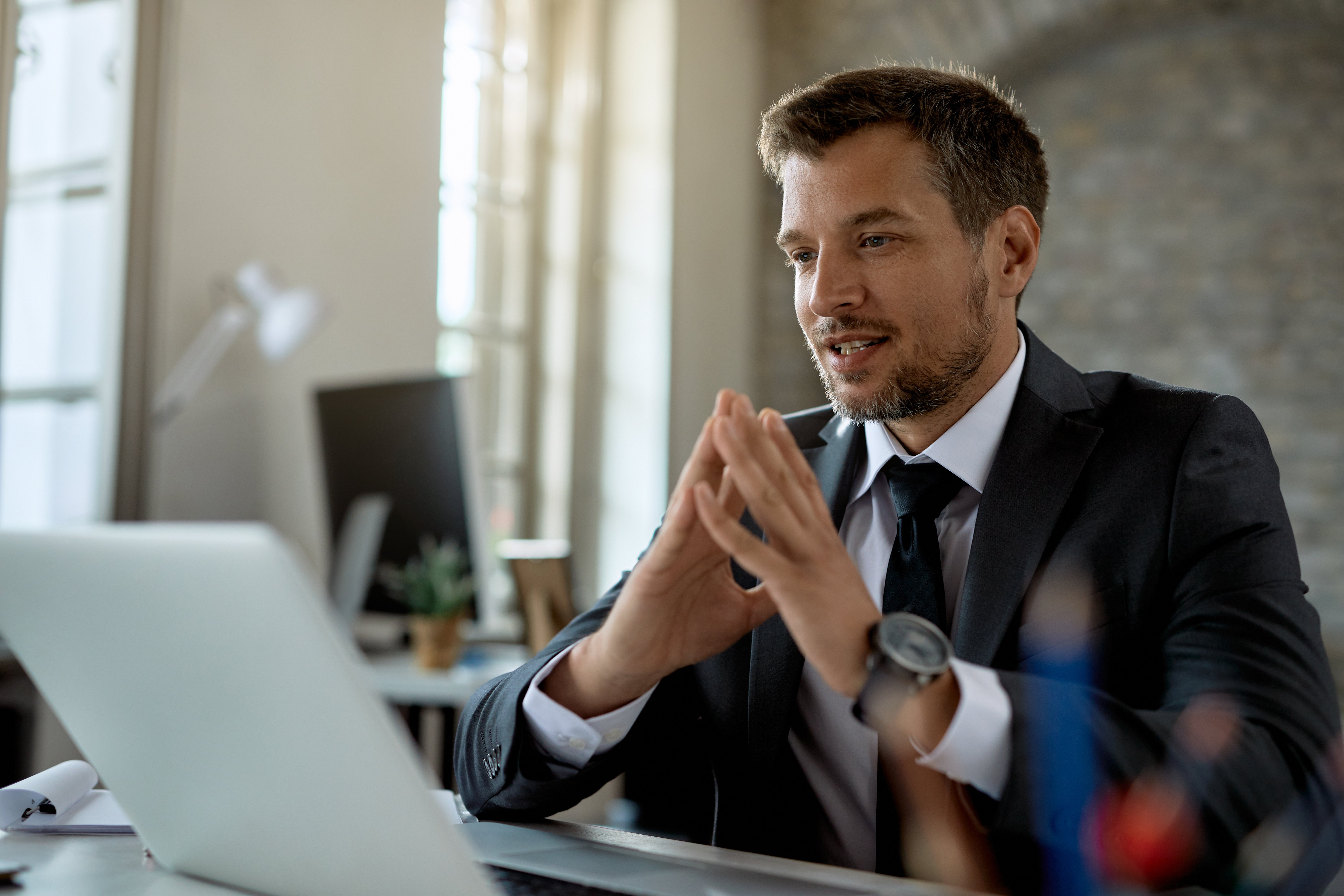 smiling-businessman-reading-email-laptop-while-working-office